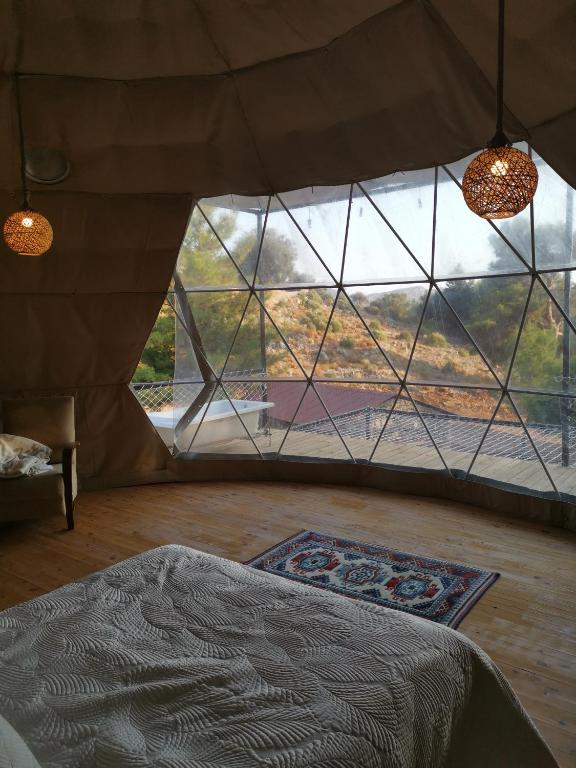 AlıncaにあるTürkdomes Glampingのベッド1台、大きなガラス窓が備わる客室です。