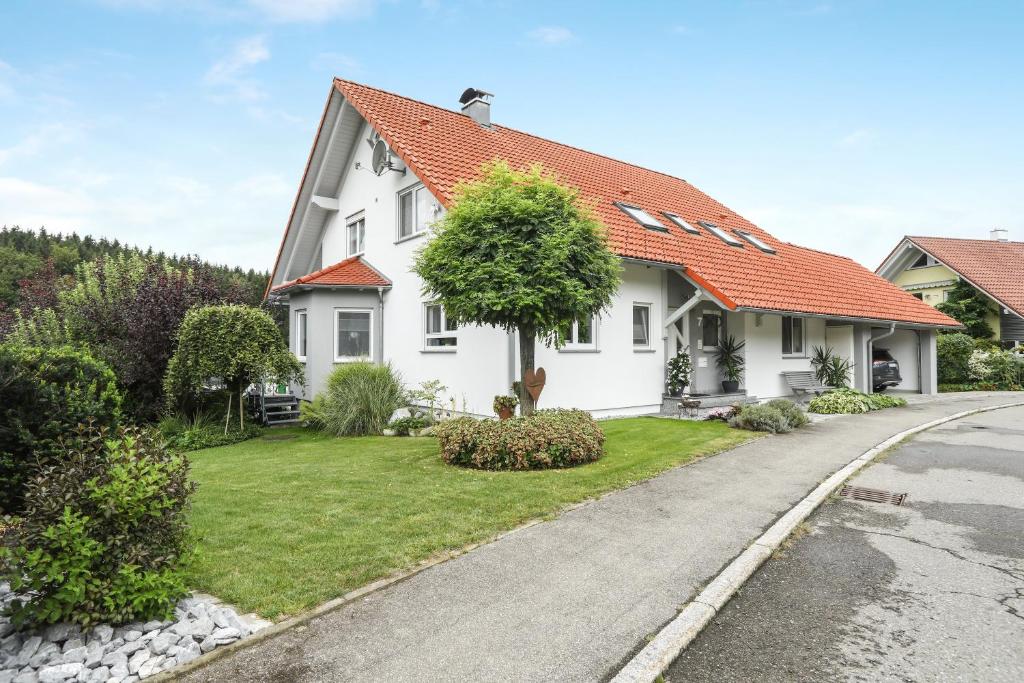ein weißes Haus mit orangefarbenem Dach auf einer Straße in der Unterkunft Ferienwohnung Merk in Neukirch