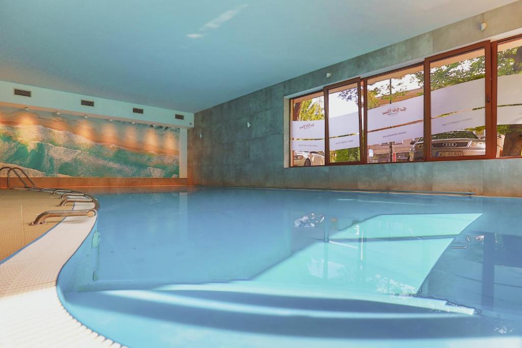 a large swimming pool with blue water in a room at Ośrodek wypoczynkowy Balt-Tur Feel Well Resort in Jastrzębia Góra