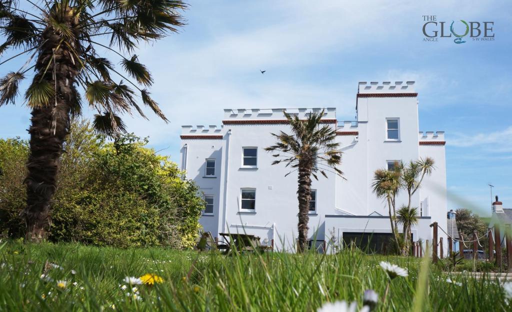 a white building with palm trees in front of it at The Globe Angle in Pembrokeshire