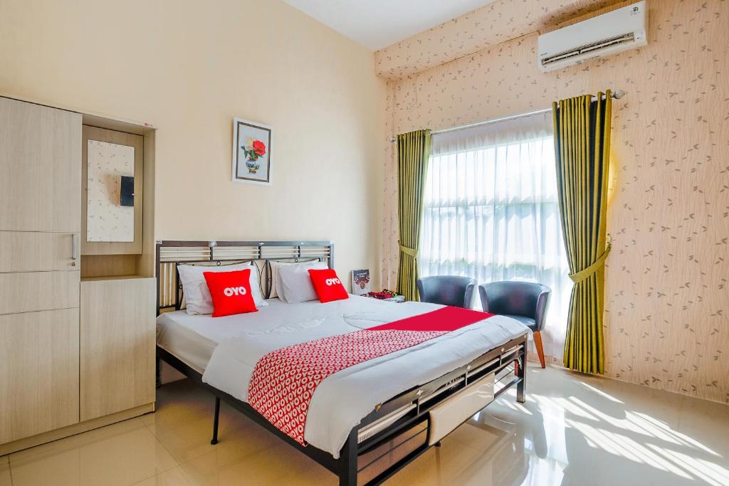 a bedroom with a bed with red pillows and a window at OYO 3434 Penginapan Keluarga Syariah in Lamongan