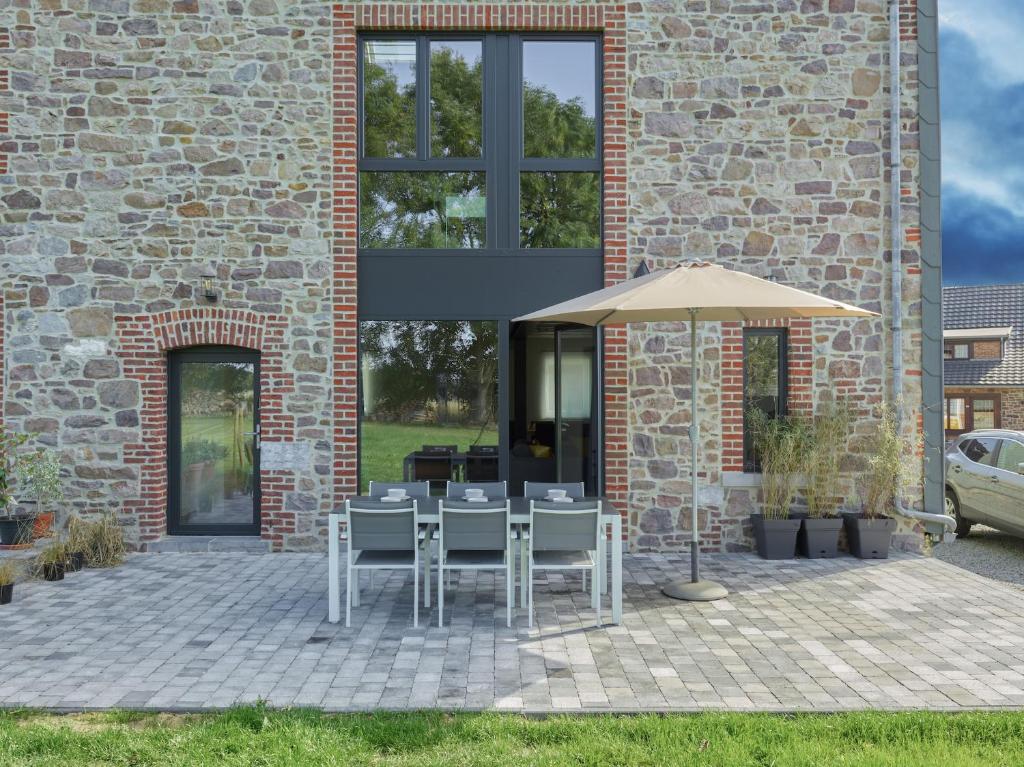 une terrasse avec une table et un parasol dans l'établissement Le Merle - Bois-de-Villers, à Profondeville