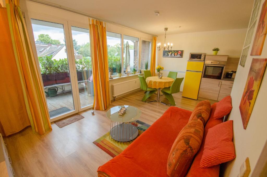 ein Wohnzimmer mit einem orangenen Sofa und einer Küche in der Unterkunft Ferienwohnung Cologne in Köln