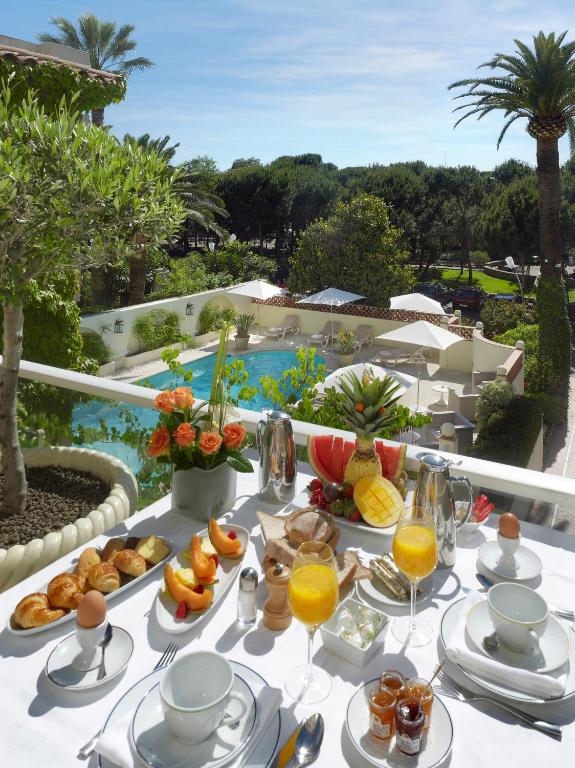a table with food and drinks on it with a pool at Hôtel Juana in Juan-les-Pins
