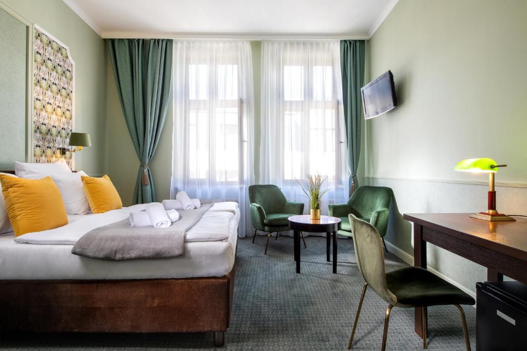 a hotel room with a bed and a desk and chairs at Amber Boutique Hotels - Hotel Amber in Kraków