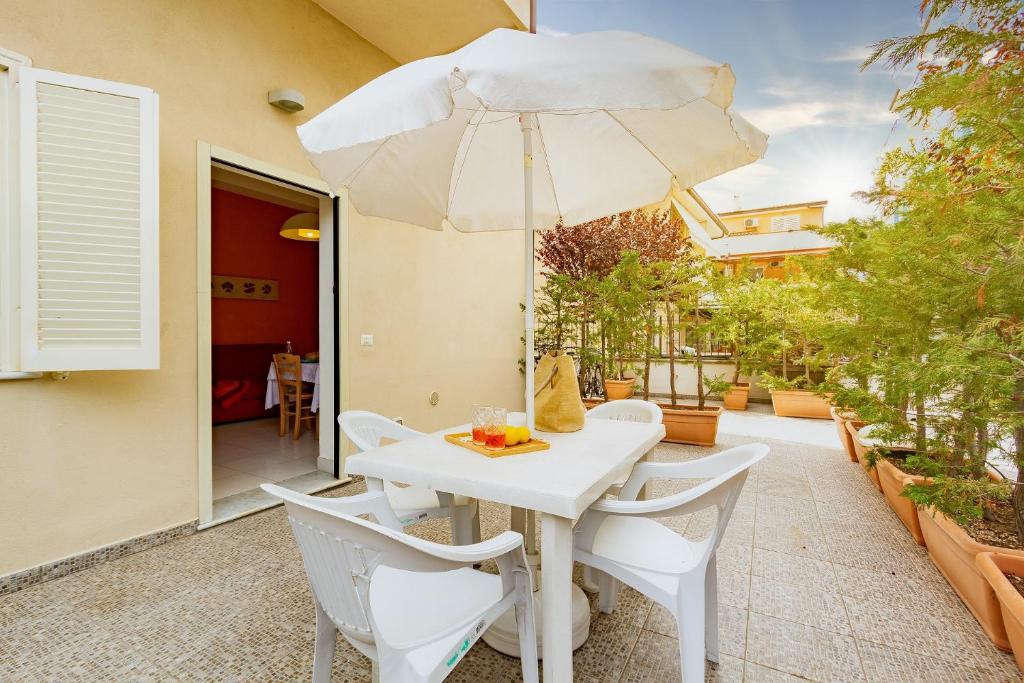 a white table and chairs with an umbrella on a patio at Appartamento Minerva int1 - MyHo Casa in Tortoreto Lido