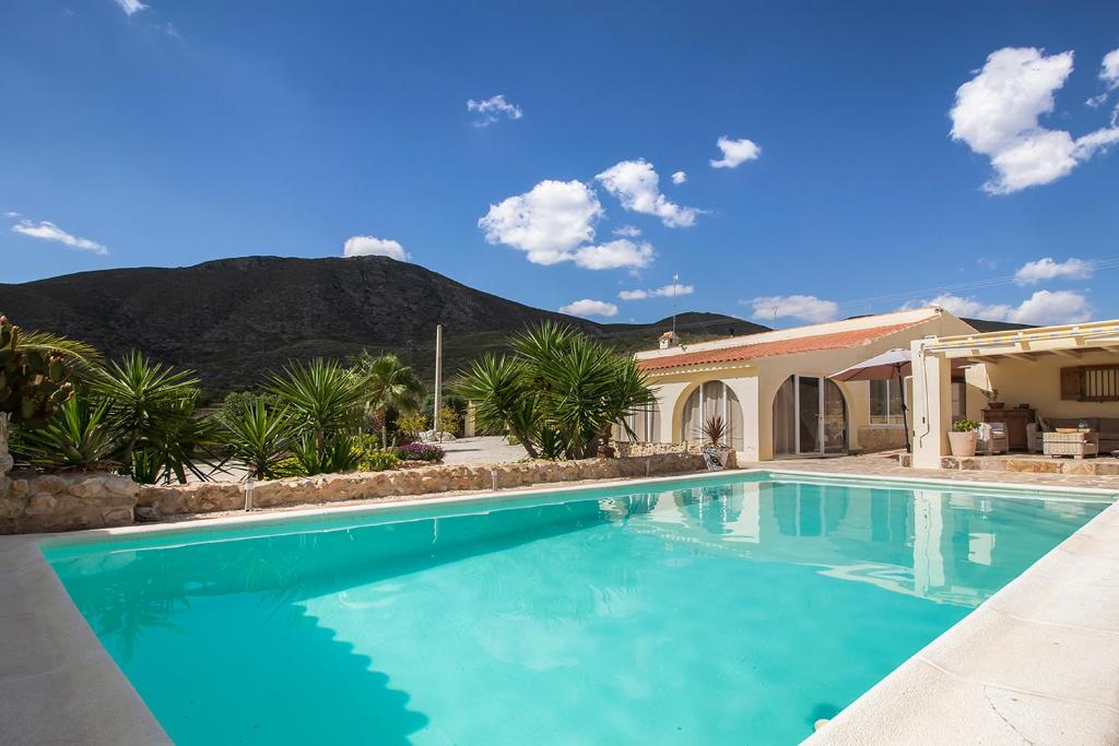 a swimming pool in front of a house with a mountain at Casa de la Piña in Hondón de los Frailes