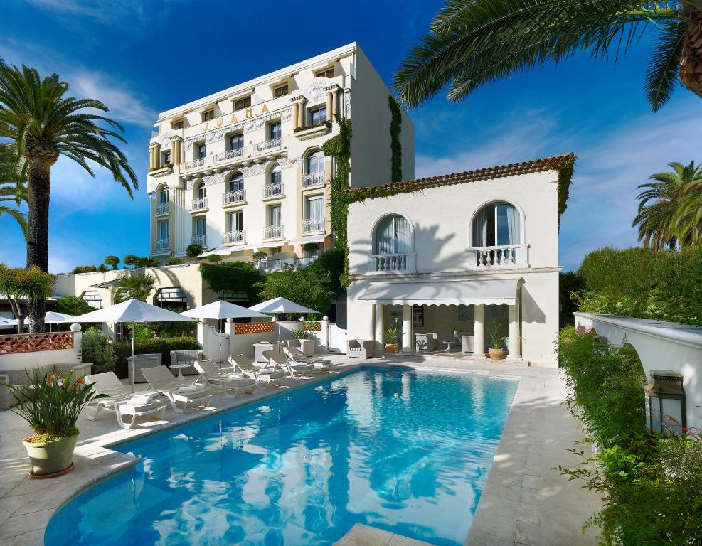 a hotel with a swimming pool in front of a building at Hôtel Juana in Juan-les-Pins