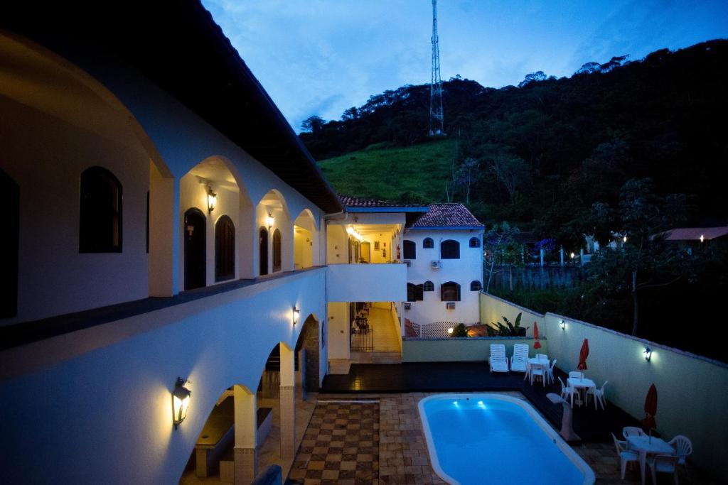 une villa avec une piscine la nuit dans l'établissement Pousada Martinez, à Conservatória