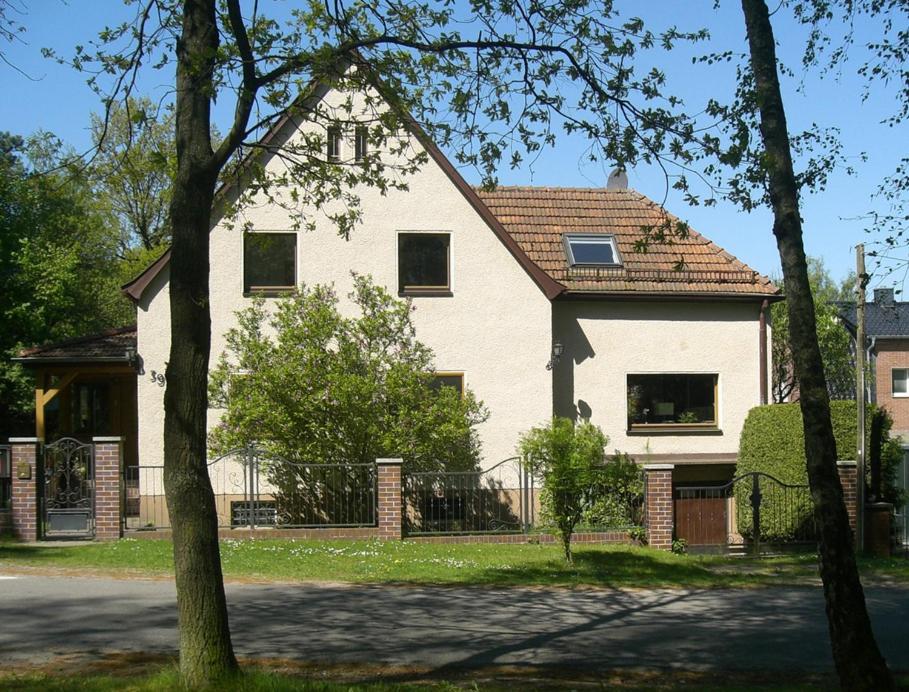 uma grande casa branca com uma cerca em frente em Ferienwohnung am Wasserturm em Hohen Neuendorf