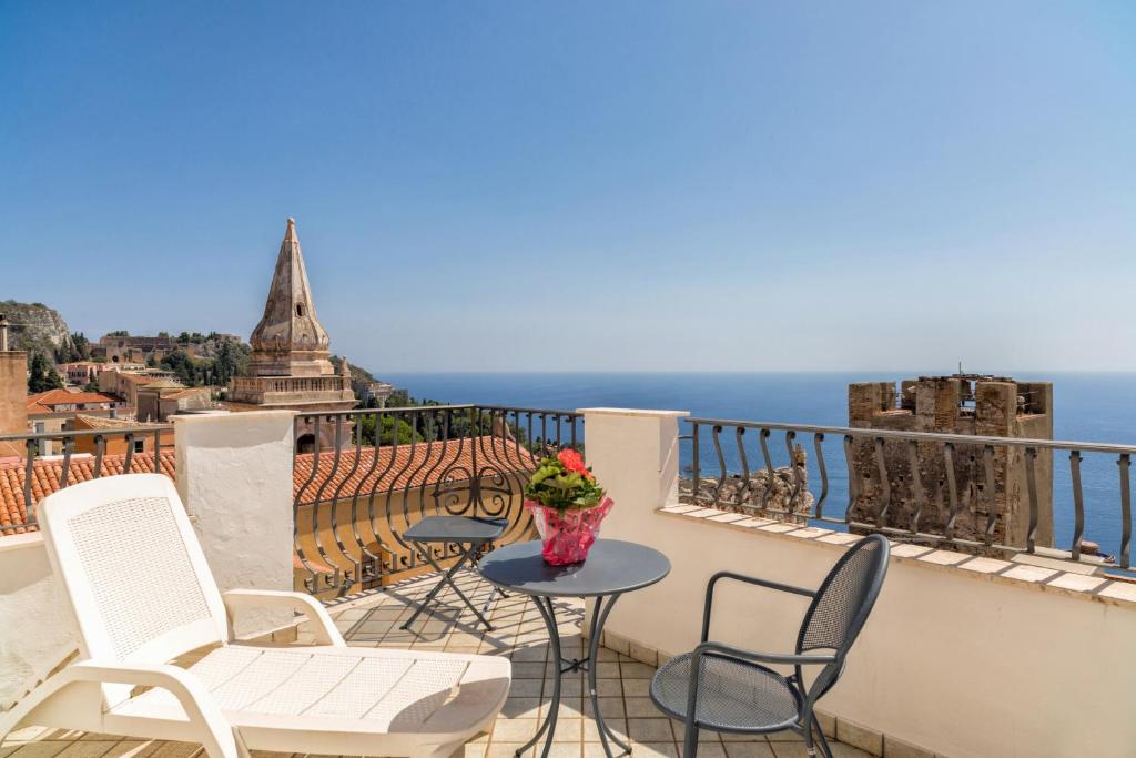 a balcony with chairs and a table with a view of the ocean at Hotel Vello d'Oro in Taormina