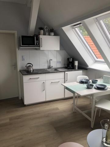 a kitchen with white cabinets and a table in a attic at Am alten Marktplatz in Norden