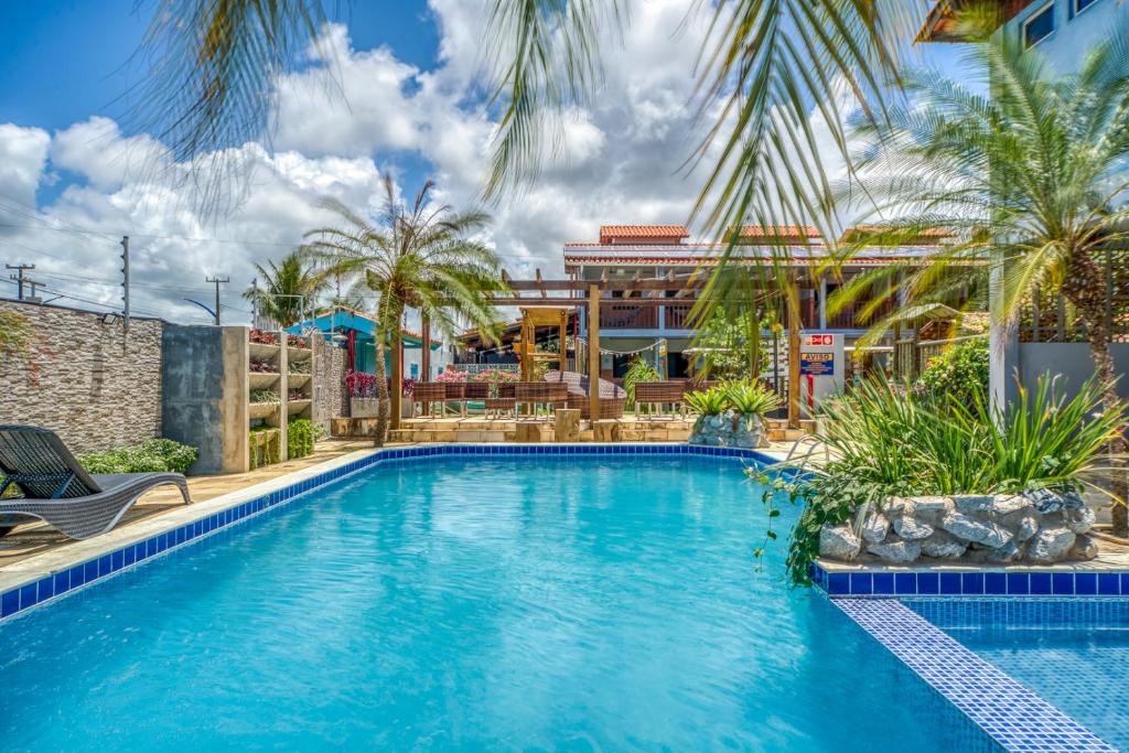 a swimming pool with palm trees and a building at Pousada Blue Viking in Praia do Frances