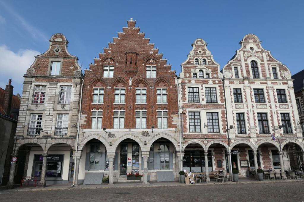 um grande edifício de tijolos com muitas janelas numa rua em Hôtel Les Trois Luppars em Arras