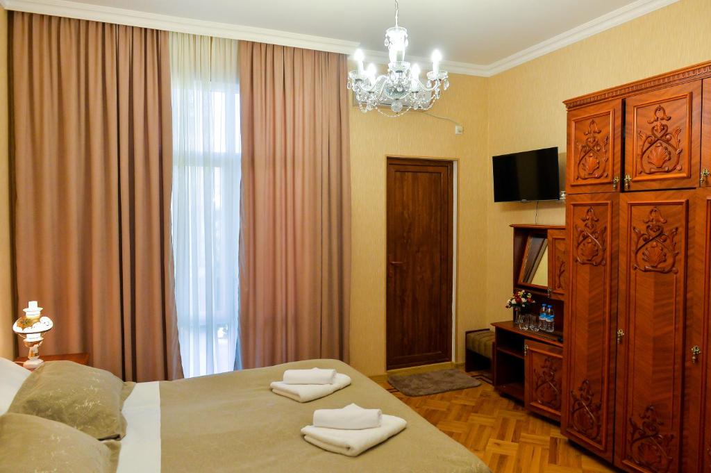 a bedroom with a large bed and a chandelier at Gold Guest House in Kutaisi
