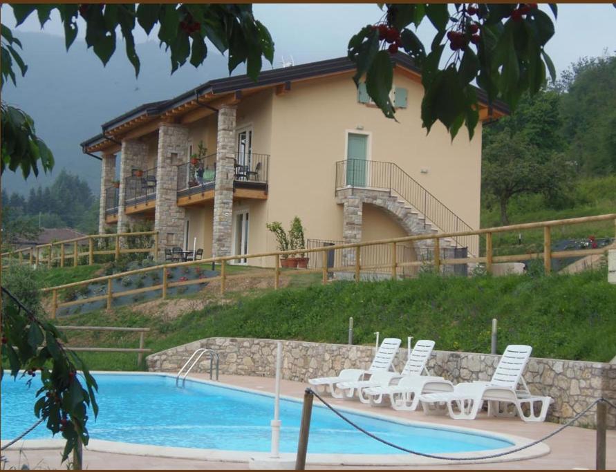a house with a swimming pool and white chairs at Casale di Pegol in Tignale