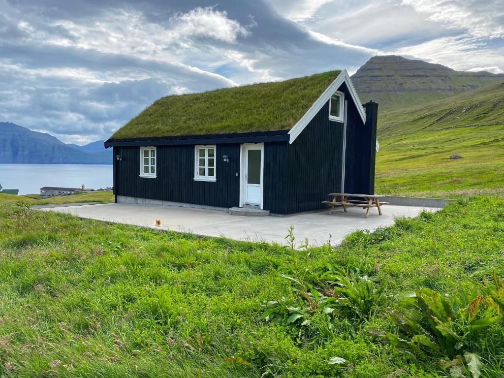 una pequeña casa negra con techo de hierba en Three bedroom vacation home, en Við Gjógv