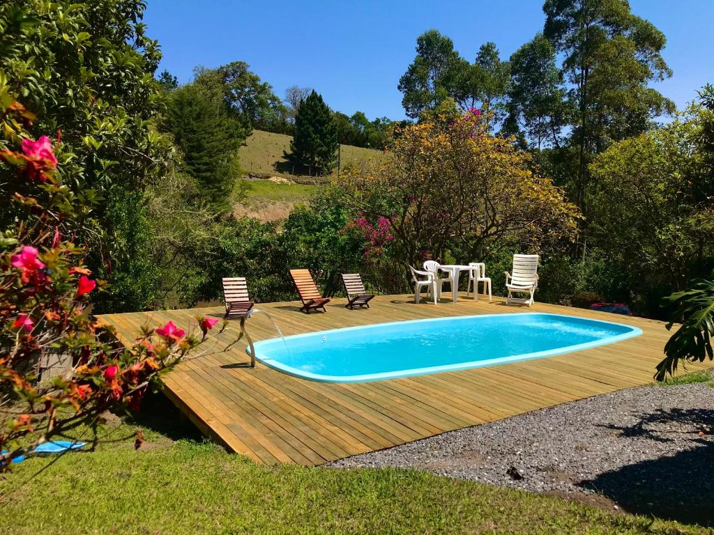 a pool with chairs and a table on a wooden deck at Sítio-Estalagem Pouso-Frio in Cunha