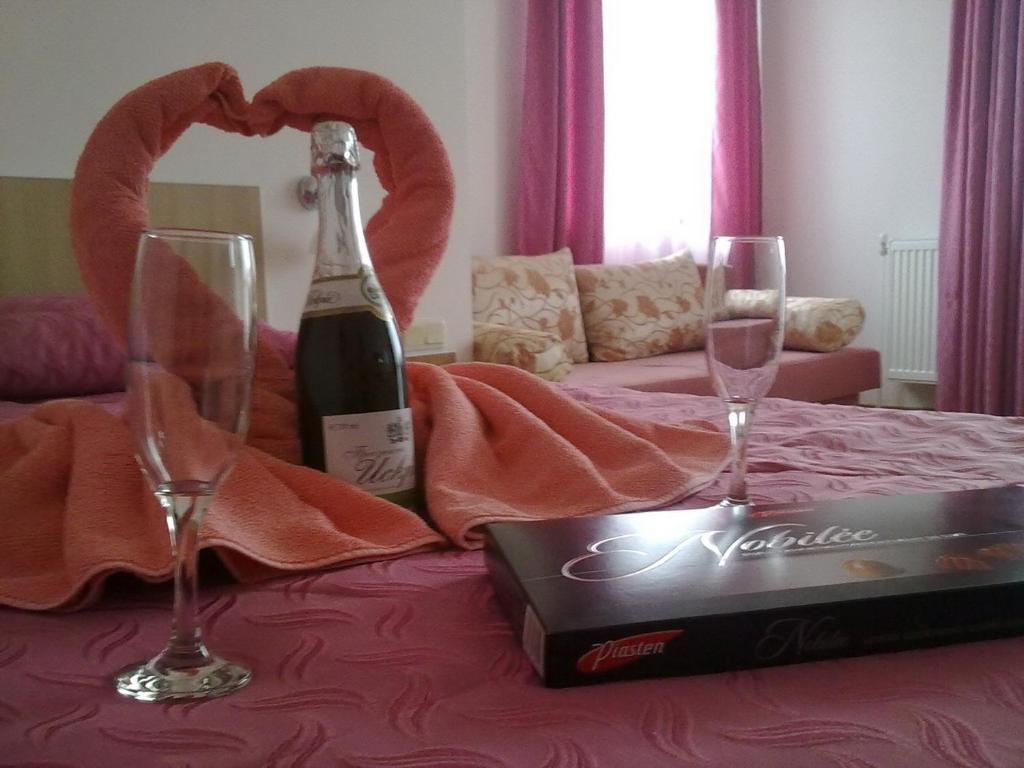 a bottle of wine and two glasses on a bed at Hotel Akre in Kavarna