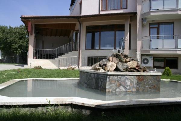 a building with a fountain in front of a house at Hotel Akre in Kavarna