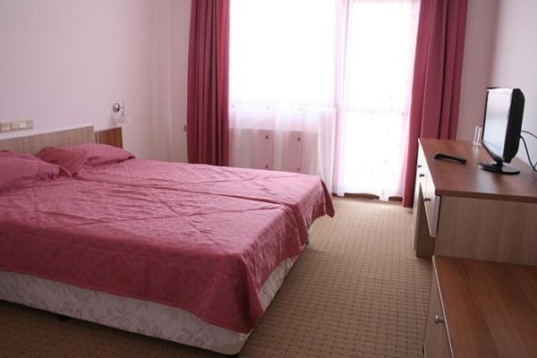 a bedroom with a bed and a desk and a television at Hotel Akre in Kavarna
