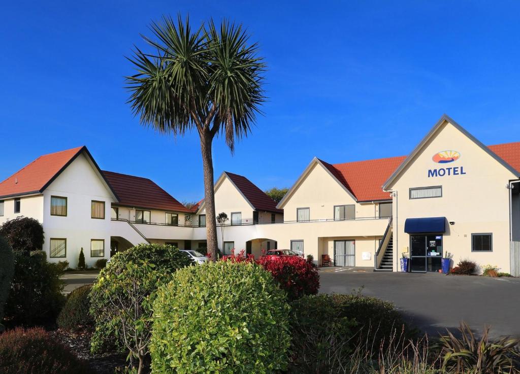 un hotel con una palmera y un motel en Bella Vista Motel Invercargill, en Invercargill