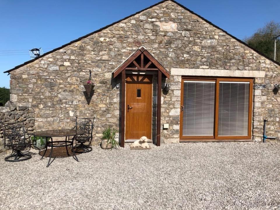 un edificio de piedra con puerta, mesa y sillas en Milo’s Retreat, en Arnside