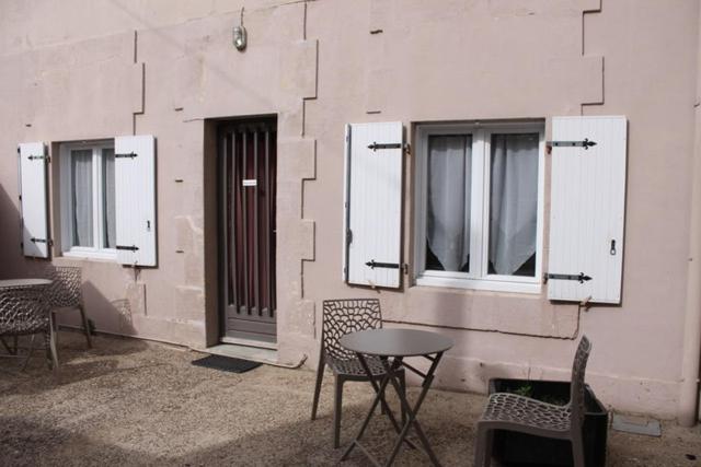 un patio con sillas, mesa y ventanas en maisonnette, 5003, en Rochefort