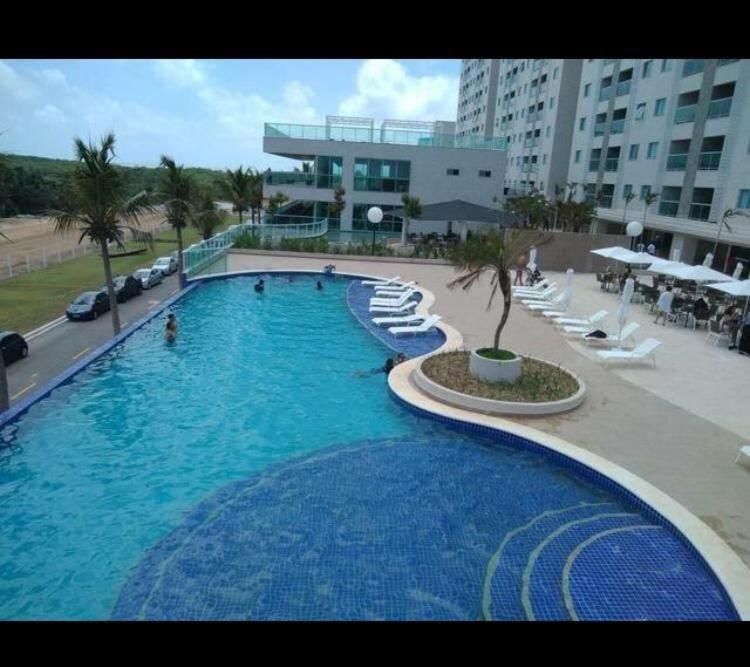 una gran piscina con sillas blancas y un edificio en apartamento em SALINAS RESORT, en Salinópolis