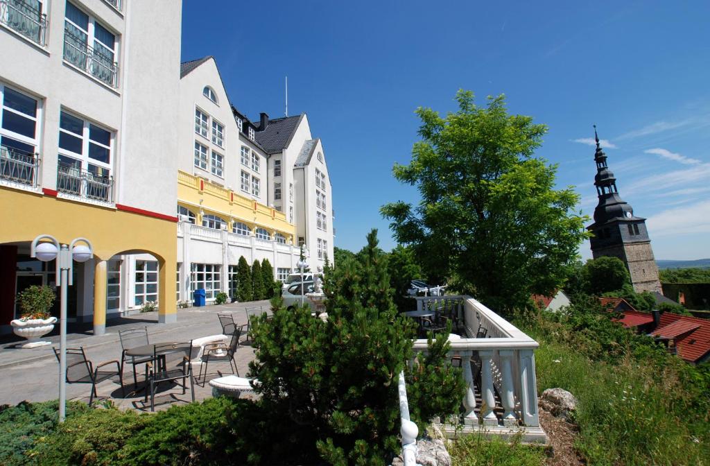 Hotel Residenz Bad Frankenhausen في باد فرانكنهاوزن: مجموعة مباني بطاولات وكراسي وبرج