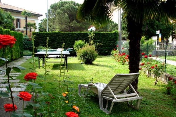 una silla y una mesa en un jardín con flores en Casa Belli Holiday Apartments Adults Only, en Arco