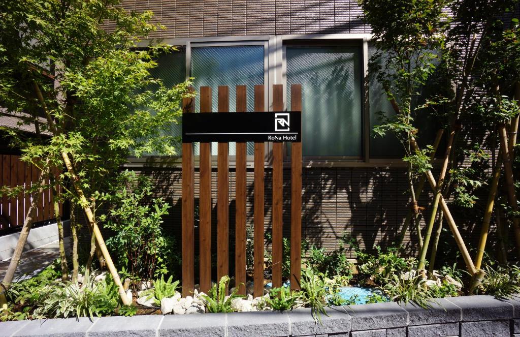 uma cerca de madeira com um sinal em frente a uma casa em RoNa Hotel em Tóquio