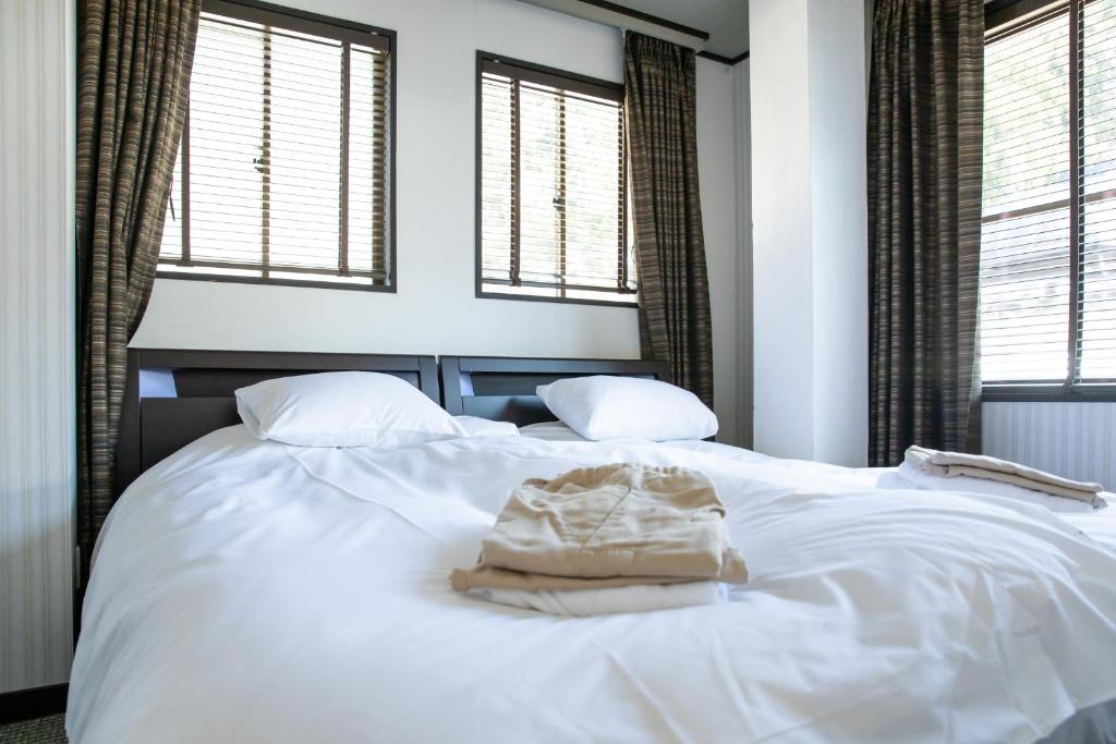 Address Nagasaka في نوزاوا أونسن: سرير أبيض مع نافذتين في غرفة النوم