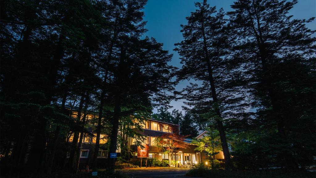 a building in the middle of a forest at night at Kyu-Karuizawa Hotel Shinonome in Karuizawa