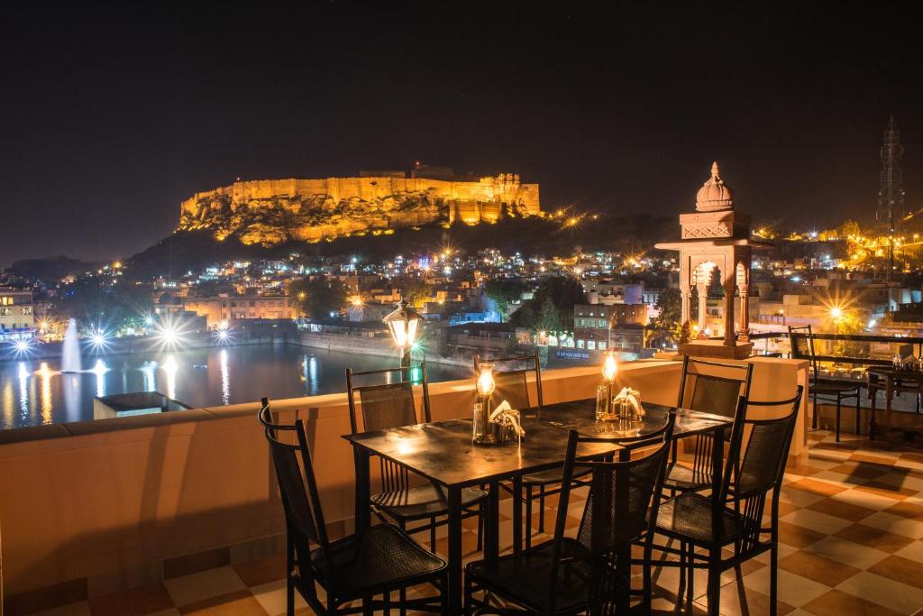 a table and chairs on a balcony with a view of the castle at Jee Ri Haveli in Jodhpur