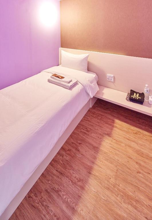 a bedroom with a white bed with a wooden floor at Single Inn - Taipei in Taipei