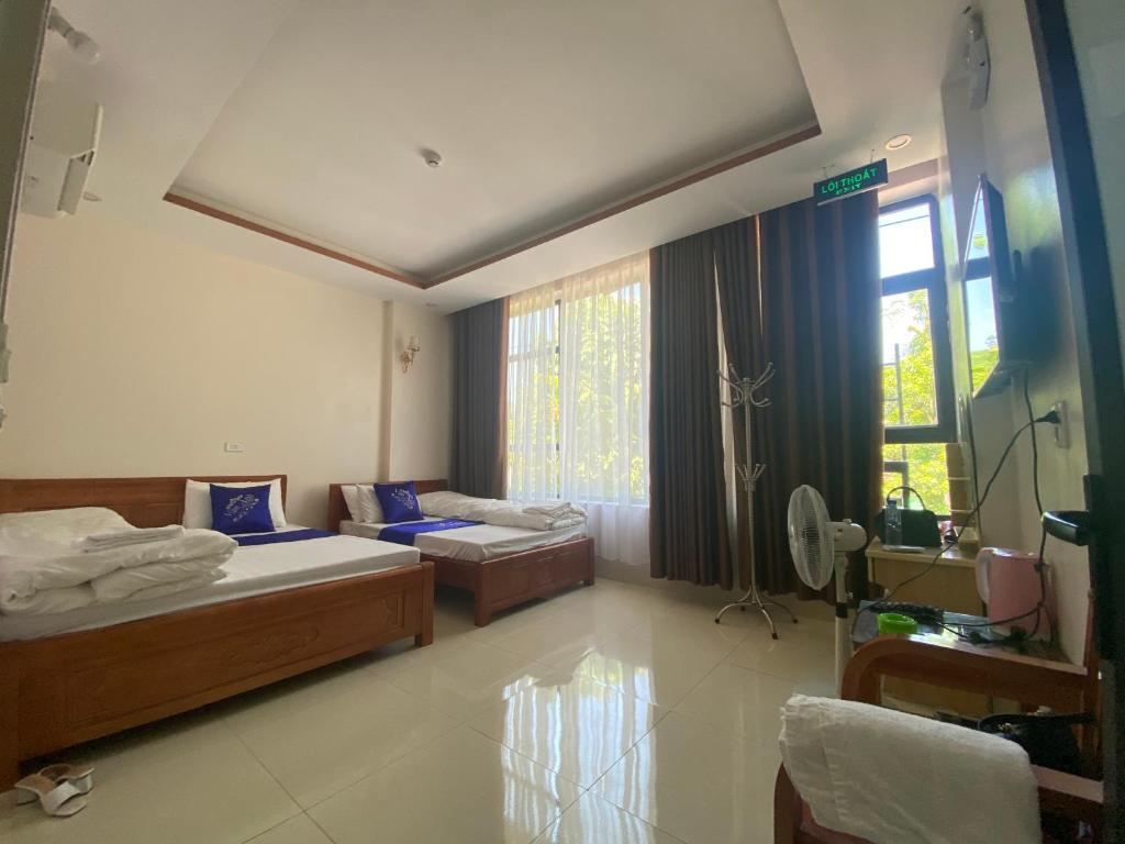 a hotel room with two beds and a window at Van Anh Motel in Cốc Lếu