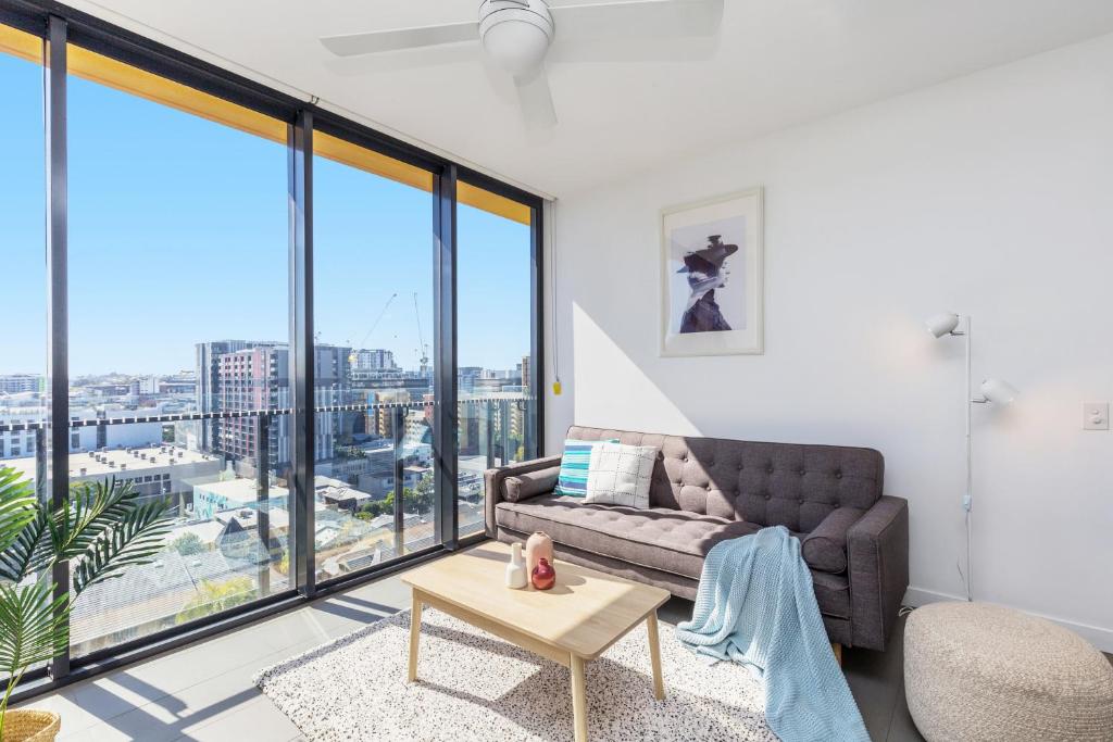 ein Wohnzimmer mit einem Sofa und großen Fenstern in der Unterkunft KOZYGURU FORTITUDE VALLEY AMAZING VIEW 2BED APT + FREE PARKING QFV010 in Brisbane