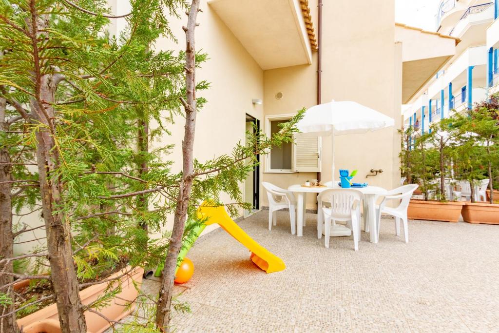 a patio with a table and chairs and an umbrella at Appartamento Minerva int2 - MyHo Casa in Tortoreto Lido