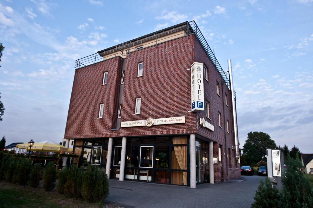 un gran edificio de ladrillo rojo con un cartel. en Hotel Manu en Paderborn