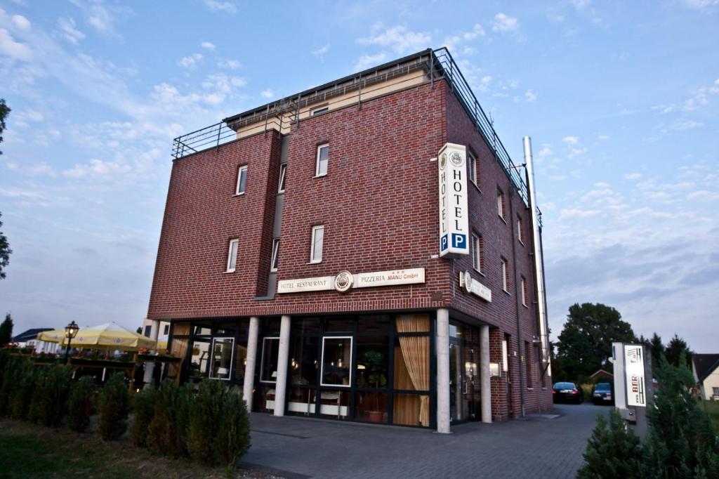 un grande edificio in mattoni rossi con un cartello sopra di Hotel Manu a Paderborn