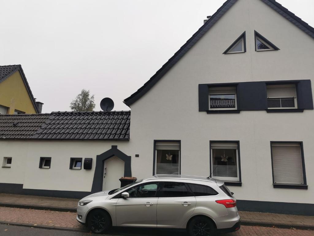 ein silbernes Auto, das vor einem weißen Haus parkt in der Unterkunft Ferienhaus Thalia in Übach-Palenberg