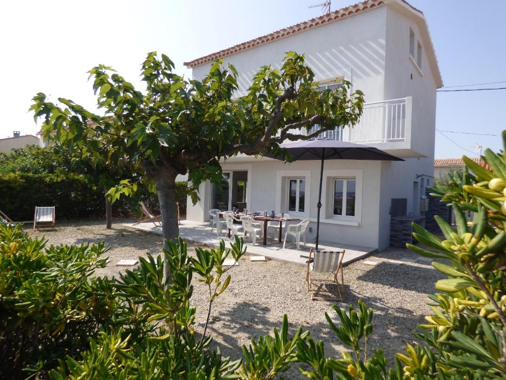 une maison blanche avec une table et des chaises dans l'établissement Villa T5 climatisée - Front de Mer - Narbonne Plage, à Narbonne-Plage