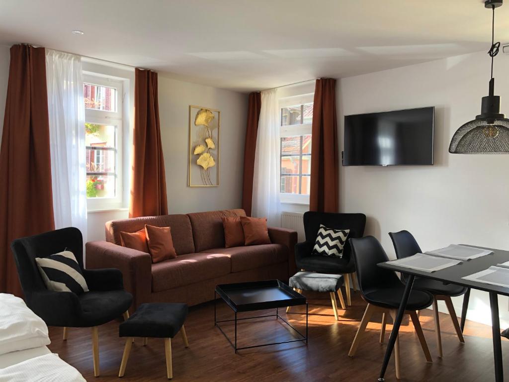 ein Wohnzimmer mit einem Sofa, einem Tisch und Stühlen in der Unterkunft Appartements am Schloss in Tübingen