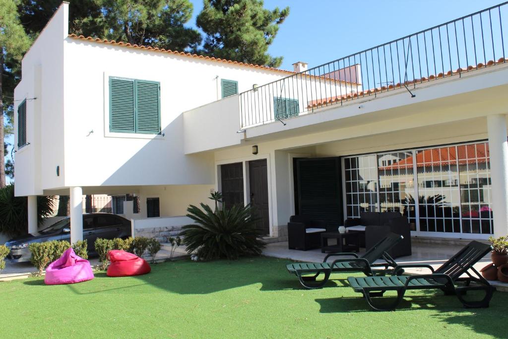 una casa con dos sillas de jardín delante en Aroeira Palm Beach Villa, en Aroeira