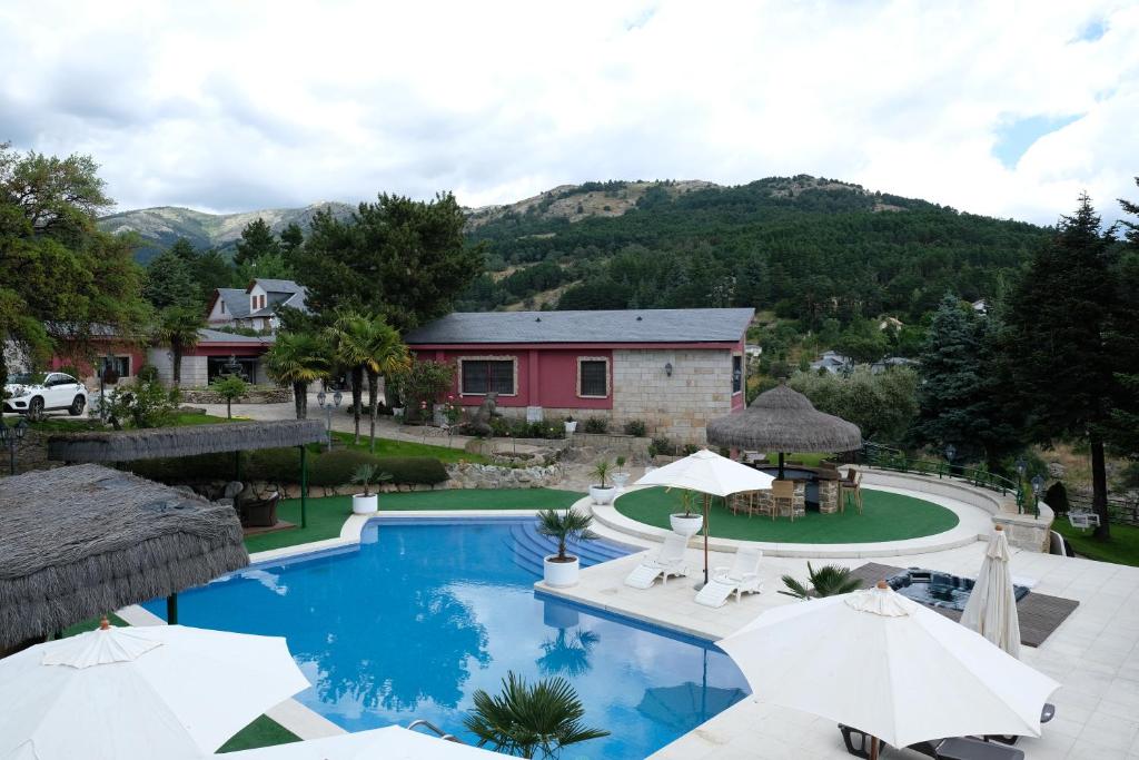 una piscina con ombrelloni di fronte a una casa di El Barranco de Miraflores a Miraflores de la Sierra