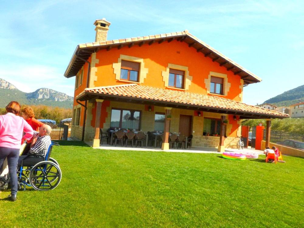 Eulz的住宿－Casa rural Navarra accesible para grupos grandes de 14-16 personas Belastegui II，坐在房子前面的轮椅上的家庭