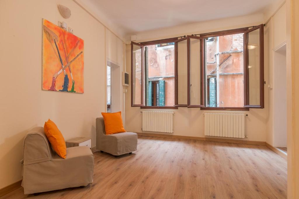 ein Wohnzimmer mit 2 Stühlen und einem Gemälde an der Wand in der Unterkunft Family Colours close to @Rialto Mercato in Venedig