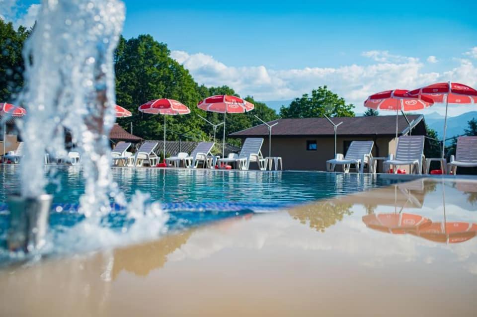 a swimming pool with a fountain with chairs and umbrellas at Хотелски комплекс САНЯ in Apriltsi