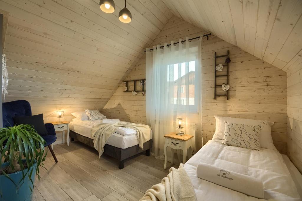 a attic bedroom with two beds and a window at Tylicz Domek na Jankowym 90m in Tylicz